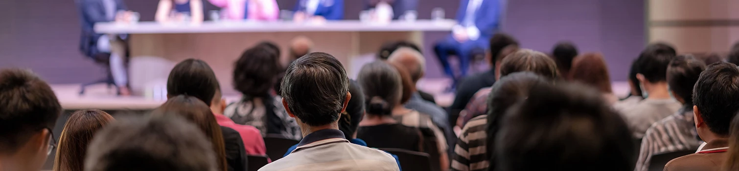 Partecipa al Simposio come Visitatore Pubblico seduto di spalle durante una conferenza scientifica del Simposio AFI che ascolta l’oratore sul palco.